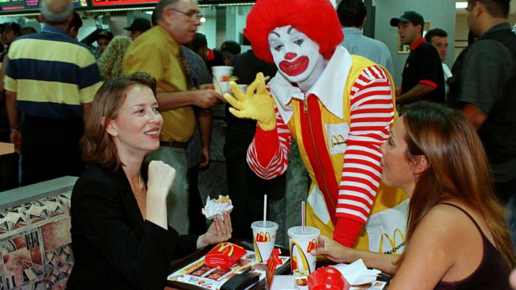 Ronald McDonald saludando a clientes dentro de un McDonald's